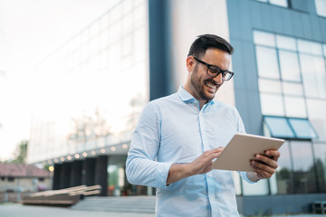 Portrait of businessman in glasses holding tablet