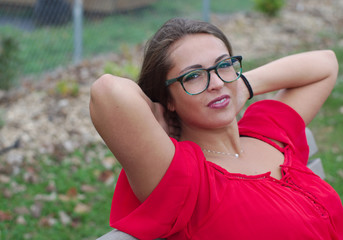 young women sitting on bench in a park red dress glasses