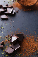 Cocoa powder in a sieve over black slate background