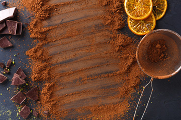 Cocoa powder in a sieve over black slate background