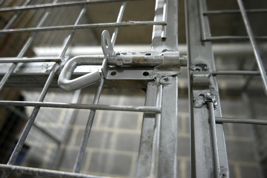 Unlocked gate of a metal storage cage with wire netting