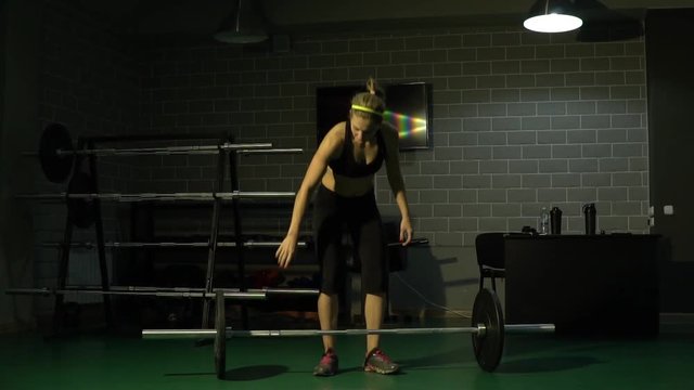 A strong woman raises a heavy weight in the gym. Slow motion