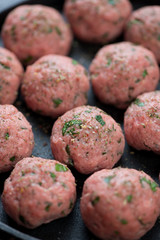 Closeup of raw beef meatballs with addition of ricotta cheese and parsley, selective focus, vertical shot