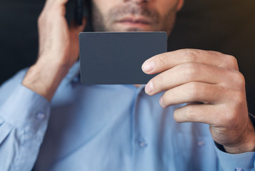 Man talking on the phone and holding credit card.