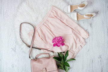 Pink blouse, bag, shoes and a peonie. Fashionable concept, white fur on the background