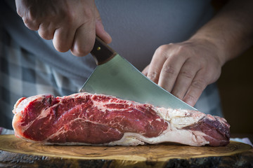Carnicero cortando carne de entrecot de ternera para la comida - obrazy, fototapety, plakaty