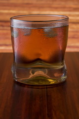 Glass of wiskey and ice on wooden background