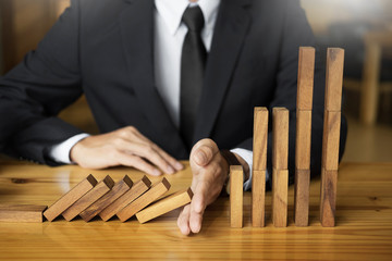 businessman hand stop dominoes continuous toppled or risk with copyspace.