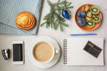 New Year's still life in the office. Bun, coffee with milk, calculator, hand holding a cup with a coffee.