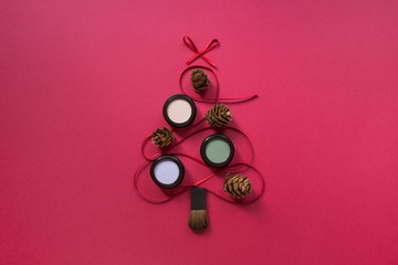 Christmas eyeshadows makeup flat lay, Christmas tree shaped ribbon on red background