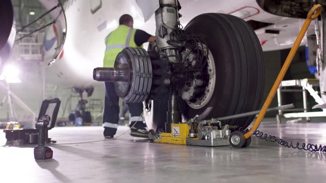 Airport worker checking chassis. Engine and chassis of the passenger airplane under heavy maintenance. Engineer checks the aircraft chassis and engine.