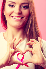Breast cancer. Woman making heart shape on pink ribbon