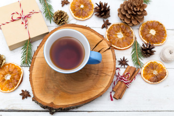 Obraz na płótnie Canvas A cup of tea stands on a wooden tray, and around the Christmas decorations. Flat lay