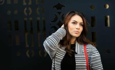 Beautiful elegant Female leaning against a modern metal gate. Downtown. City