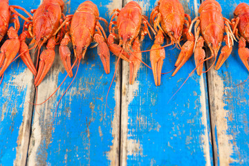 Row of whole red boiled crawfish on old rustic blue wooden planks