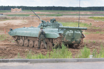 Fototapeta premium Russian tank with detachment of Marines on maneuvers in the field. One unidentified soldier with a gun and ammunition in fighting near the machine.