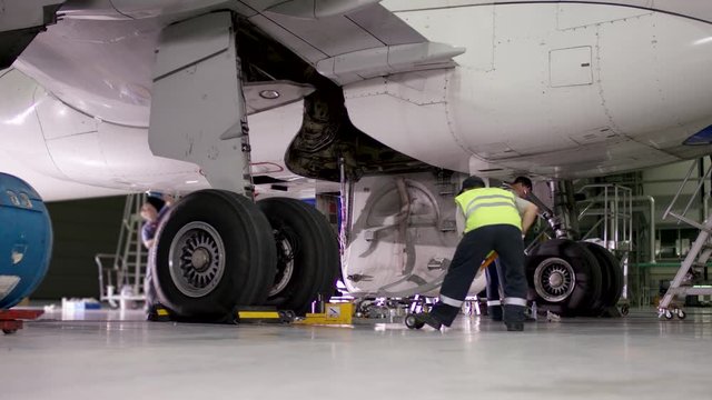 Inspection and preparing the aircraft before take off. Maintenance of passenger aircraft chassis at hangar before flight. Airport workers mechanic