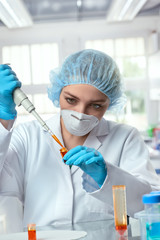 Young female tech or scientist loads liquid sample into test tube