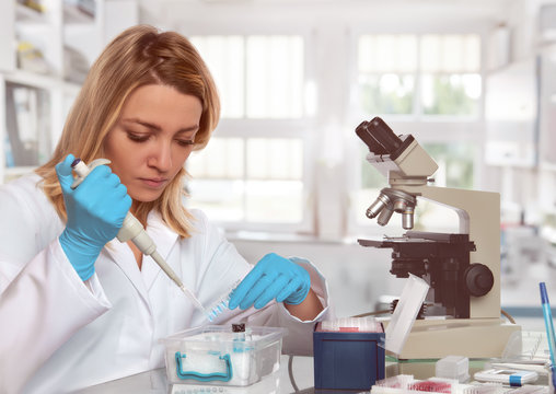 Young female tech or scientist loads liquid sample into test tubes