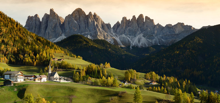 Church of St. Magdalena in front of the Geisler or Odle Dolomites mountain peaks. 
Val di Funes valley in Italy. Autumn season. 
