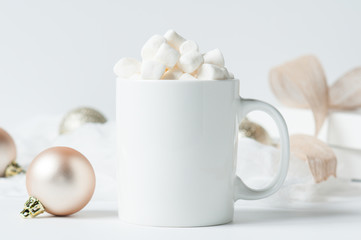 mug of hot chocolate with marshmallows surounded by Christmas decorations