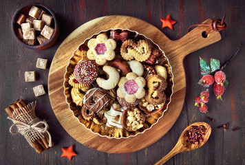 Plate of Christmas cookies on a wooden board on dark rustic background