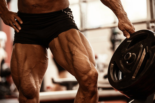Close-up of bodybuilders muscular legs. Athlete man doing workout exercise  in gym. Photos | Adobe Stock