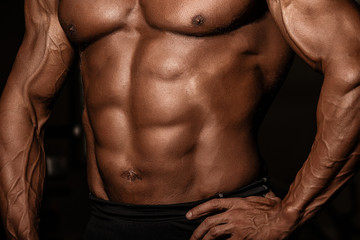 Fototapeta premium Cropped picture of muscular male tanned torso of bodybuilder. Strong athlete man with perfect abs, shoulders, biceps, triceps and chest.