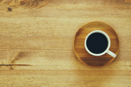 top view image of cup of coffee on wooden table.