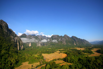 Fototapeta na wymiar Beautiful mountains scenery in spring.View at a mountain range with morning fog in a mountain valley in Vang vieng, Laos