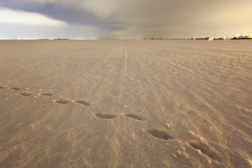 Footprints On Snow Covered Field At Night