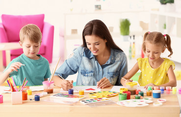 Fototapeta premium Szczęśliwa rodzina maluje obrazy przy stole w pomieszczeniu