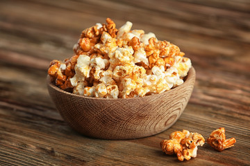 Bowl with tasty caramel popcorn on wooden table