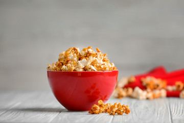 Bowl with tasty caramel popcorn on wooden table