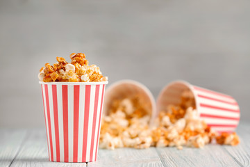 Cup with tasty caramel popcorn on wooden table - obrazy, fototapety, plakaty