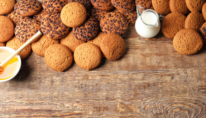 Composition with oatmeal cookies, milk and honey on wooden background