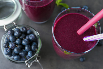 Glass with acai juice and berries in jar on table