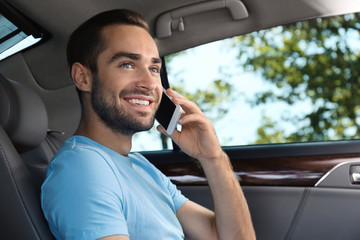 Handsome young man talking on mobile phone in car