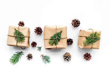 Gifts for new year wrapped in craft paper near spruce branches and cones on white background top view
