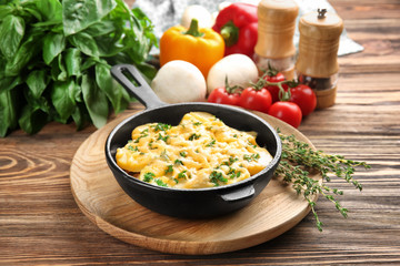 Board with potato casserole in pan on wooden table