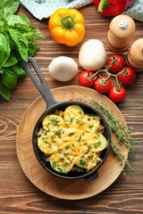 Board with potato casserole in pan and vegetables on wooden table