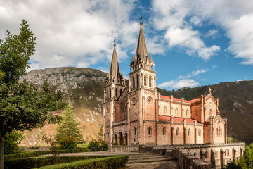 Fototapeta na wymiar Basilica of Santa Maria la Real de Covadonga, Asturias, Spain, Europe. Beautiful church of touristic travel destination in autumn with a vibrant colorful sky and green natural forest with mountains.