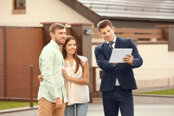 Young couple with real estate agent near house