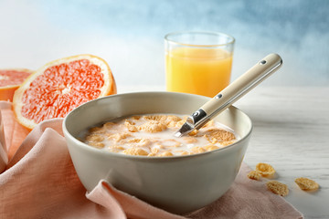 Dish with cornflakes and milk on table