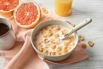 Dish with cornflakes and milk on table