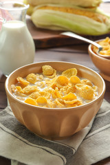 Plate with cornflakes and milk on table