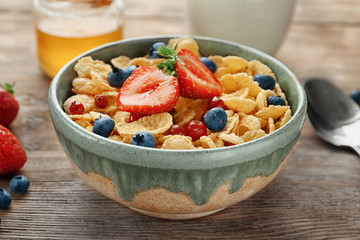 Dish with cornflakes and berries on table
