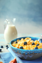 Dish with cornflakes and milk on table