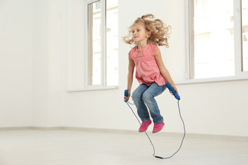 Cute girl skipping rope in light room © Africa Studio