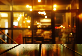 top of wood table with blur orange light party in pub or bar background